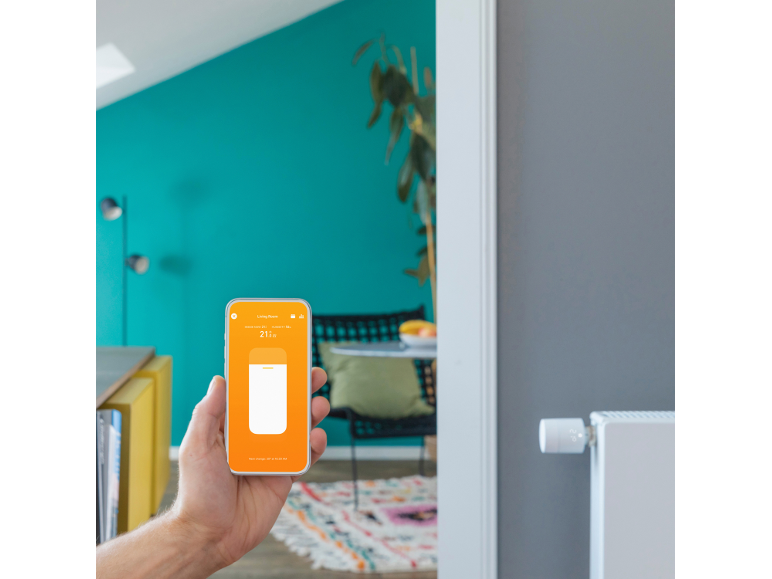 Een hand houdt een smartphone vast met een app voor slimme thermostaatbediening.