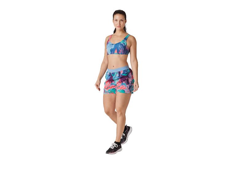 Vrouw in sportieve top, short en sneakers met bloemenprint.