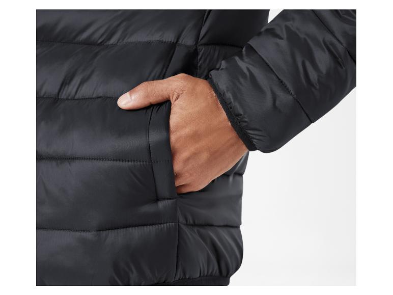 Een close-up van een zwarte pufferjas met een hand in de zak.