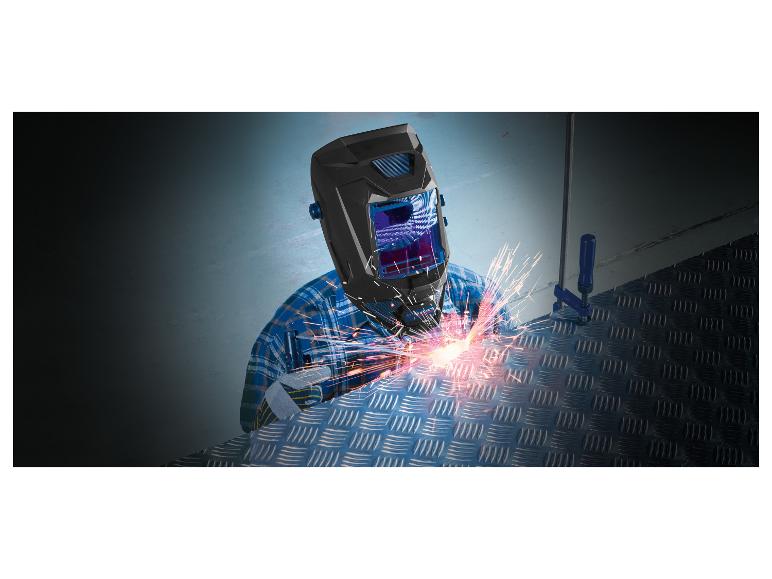 Lasser met beschermkap en handschoenen last een metalen plaat.