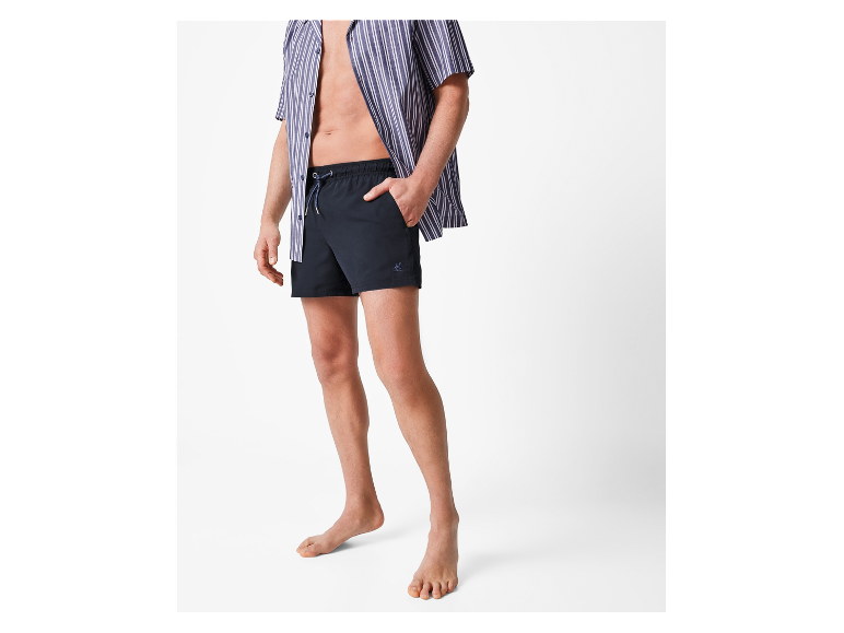 Een man in een gestreept overhemd en een zwarte zwembroek.