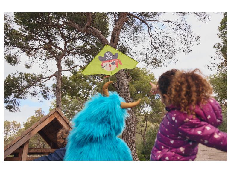 Kinderen spelen met een vlieger en een blauw knuffeldier buiten.