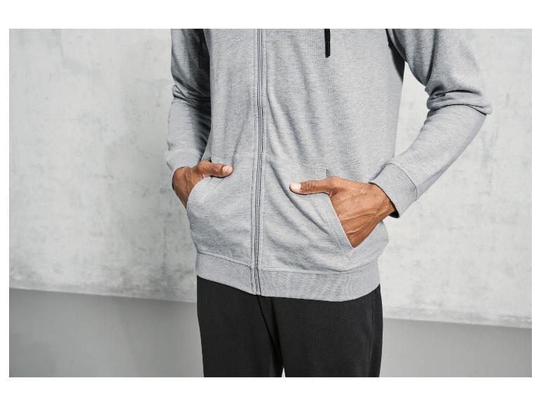 Man draagt ​​een grijze hoodie met rits en zwarte broek