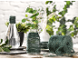 Decoratieve vazen met groen touw, planten en een bol touw op een houten tafel.