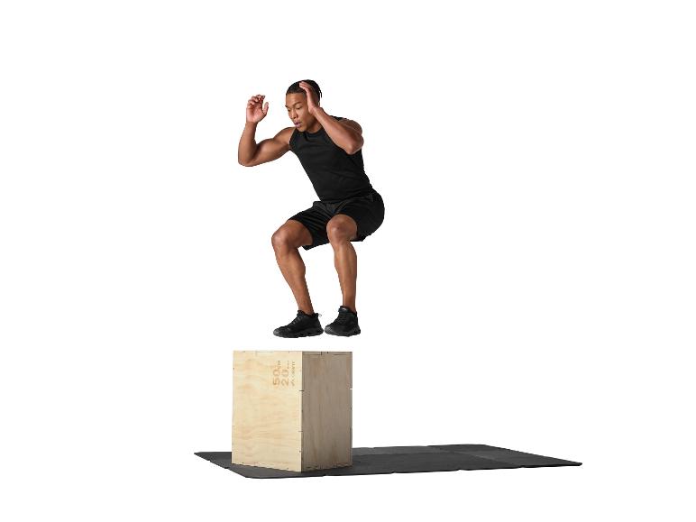 Man springt op een houten kist, zwevend in de lucht erboven.