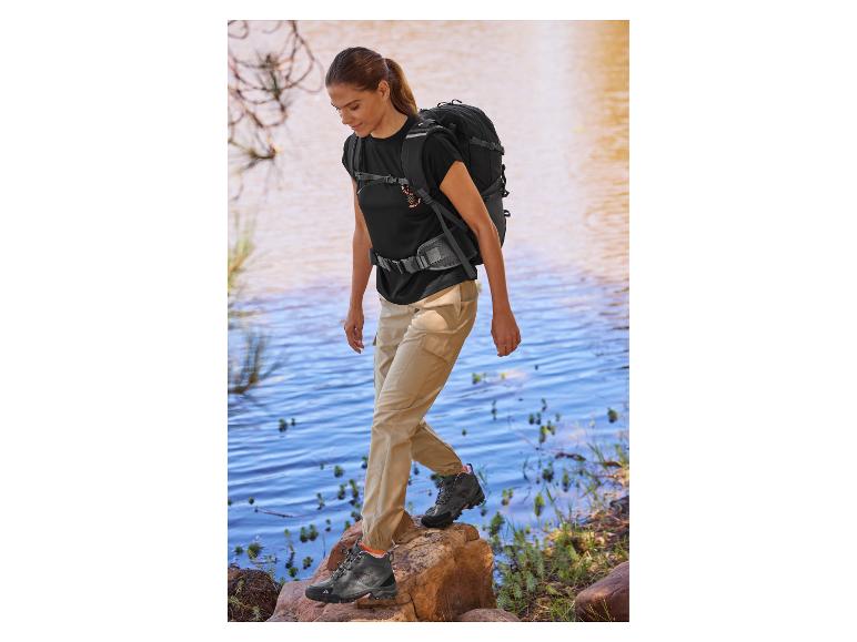 Vrouw wandelt met rugzak en wandelschoenen.