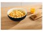 Popcorn in een zwarte kom met sinaasappeldrank en noten op een houten tafel.