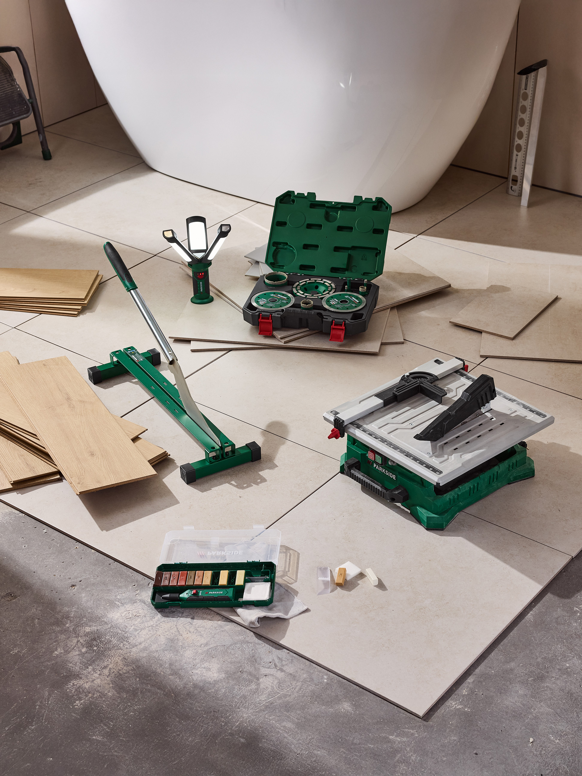 Parkside tegelsnijder, tegelzaag en reparatieset op een tegelvloer naast een badkuip.