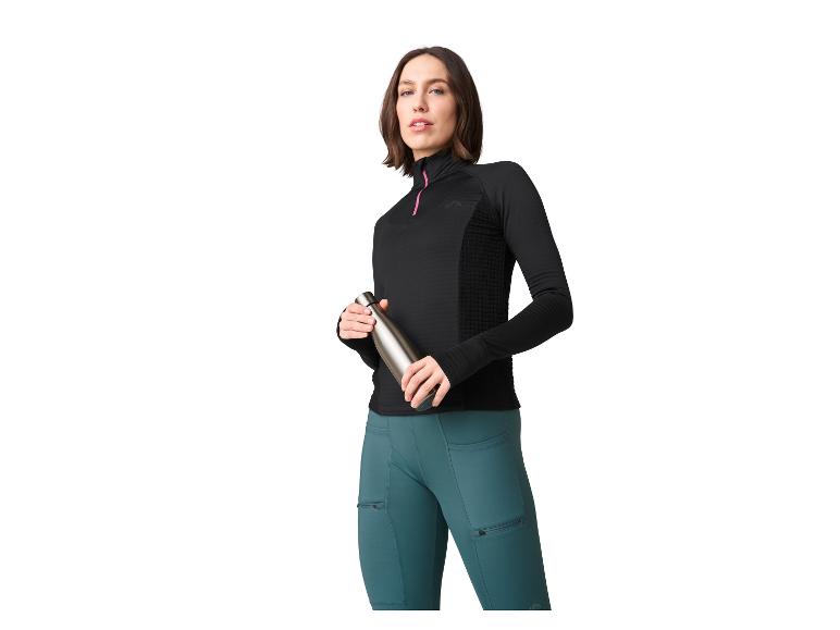 Vrouw in zwart sporttop en blauwe leggings houdt een waterfles vast.