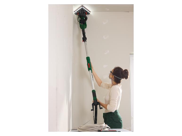 Een vrouw gebruikt een Bosch schuurmachine aan een plafond.