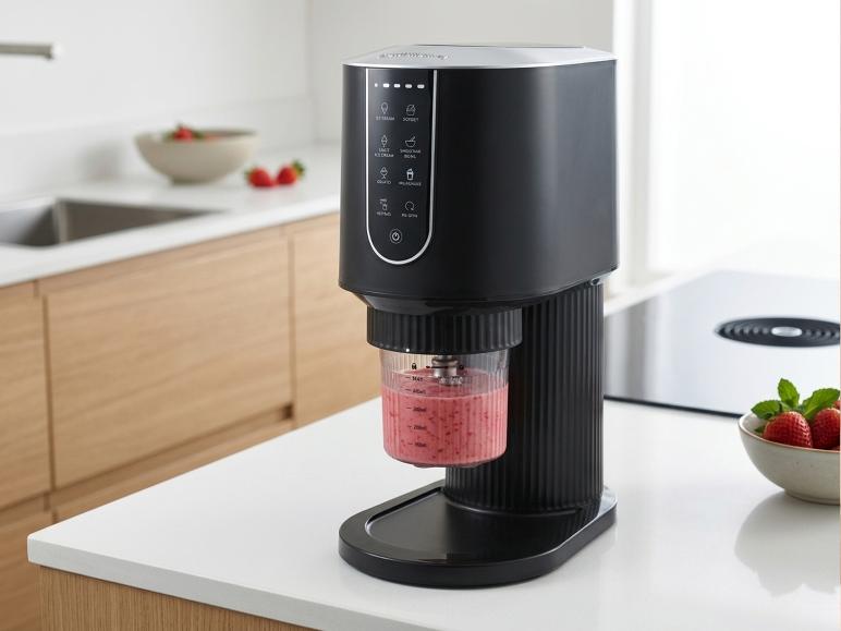 Zwarte ijsmachine met aardbeiensmoothie in een moderne keuken.
