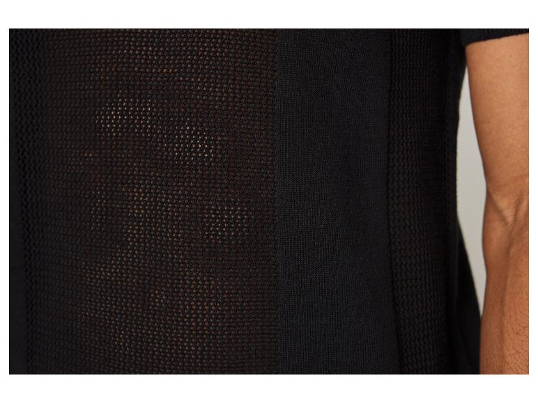 Detail van een zwart gebreid shirt met opengewerkte panelen.