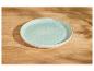 Een lichtblauw gespikkeld keramisch bord op een houten tafel met schaduwen.