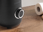 Zwarte blender met bedieningsknop en een rol keukenpapier op een houten tafel.