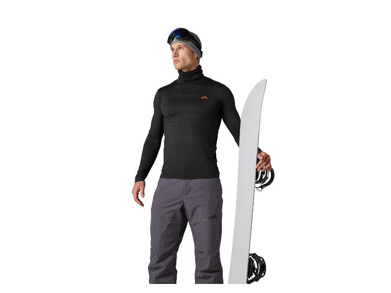 Man in zwarte en grijze snowboarduitrusting, met een wit snowboard.