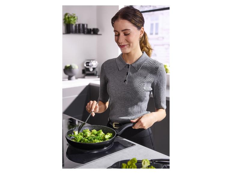 Vrouw bakt broccoli in een koekenpan op een inductiekookplaat in de keuken.
