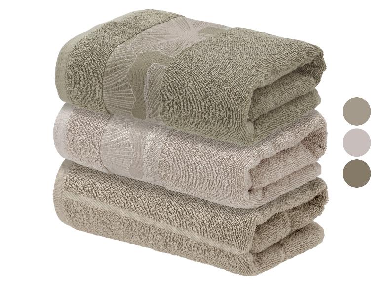 Stapel van drie katoenen handdoeken met bladdesign in beige en olijfgroene tinten.
