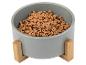 Grijze kom met houten standaard, gevuld met droogvoer voor huisdieren.