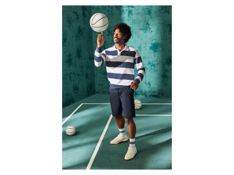 Man in gestreept poloshirt en donkerblauwe short op een basketbalveld.