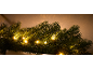 Close-up van een feestelijke groene slinger met warmwitte LED-lampjes tegen een beige achtergrond.