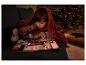 Kind leest een prentenboek met een UV-zaklamp onder een deken bij de kerstboom.