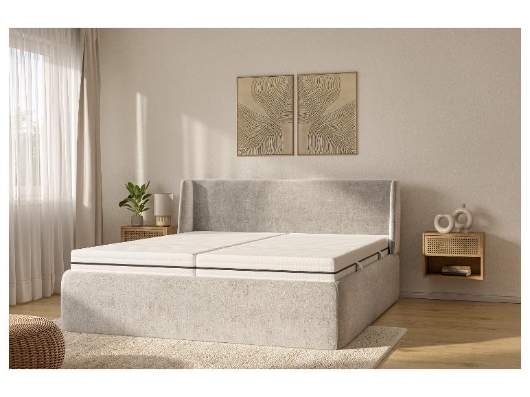 Een grijs gestoffeerd bed met een wit matras in een moderne slaapkamer.