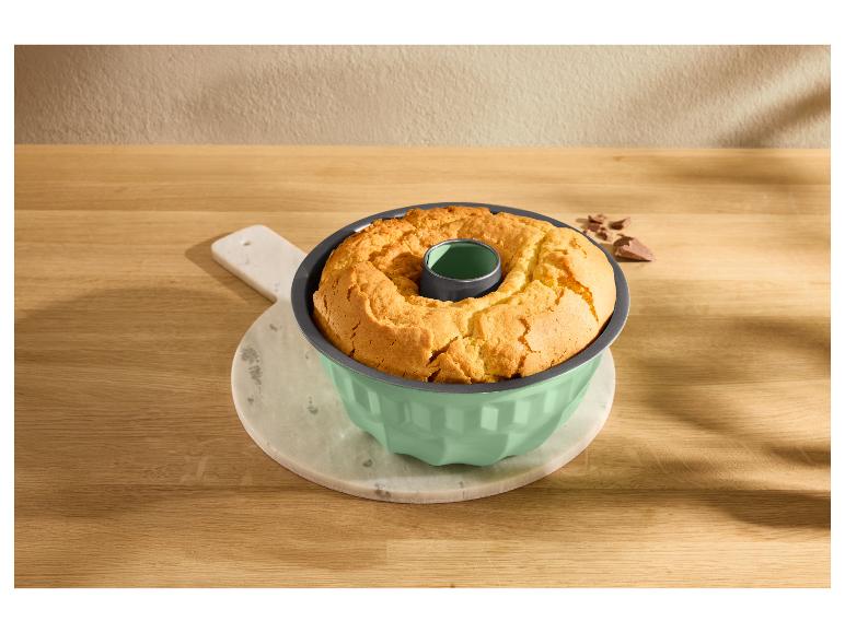 Gouden Bundt cake in een mintgroene vorm op een marmeren snijplank.