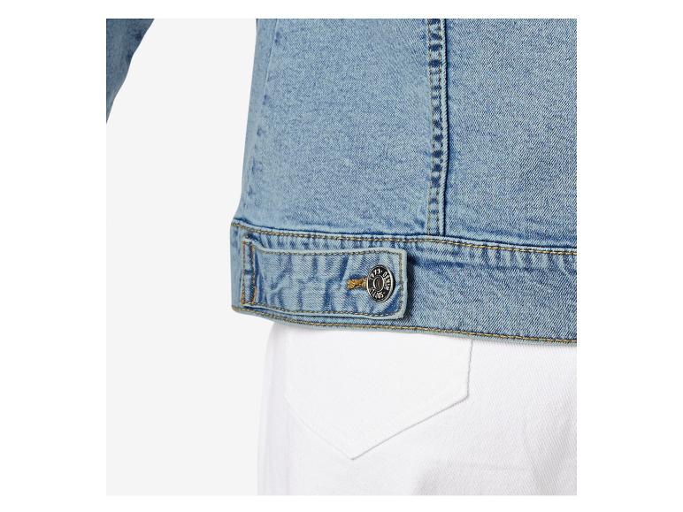 Close-up van een lichtblauwe spijkerjas met een metalen knoop en gele stiksels.