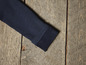 Een close-up van de manchet van een donkerblauwe trui.