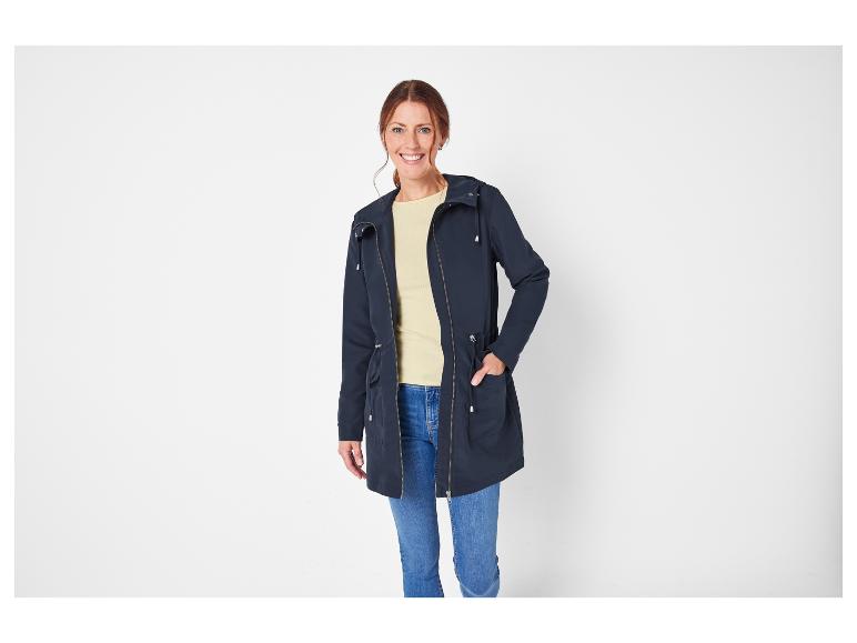 Een vrouw draagt een blauwe jas met capuchon en jeans.