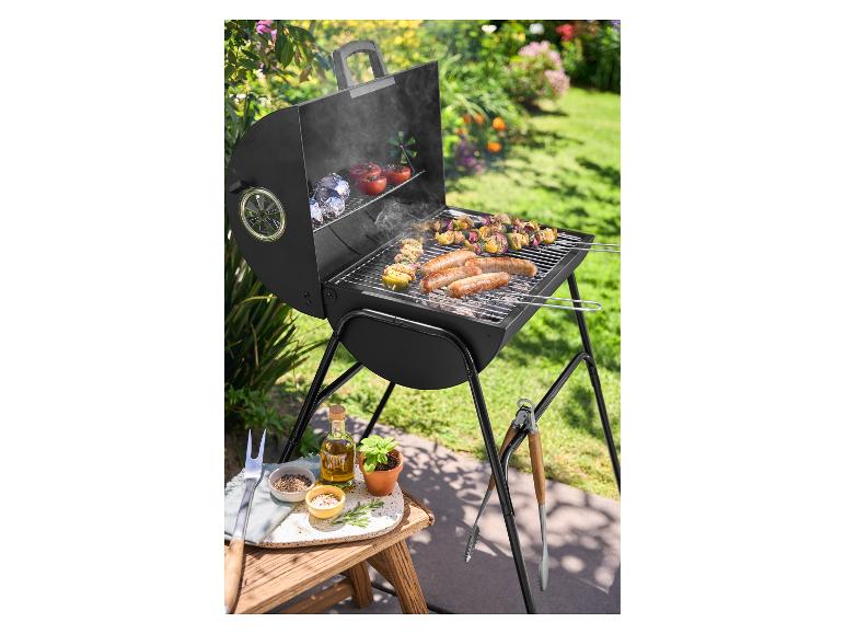 Houtskoolbarbecue met worstjes en spiesjes in een zonnige tuin.