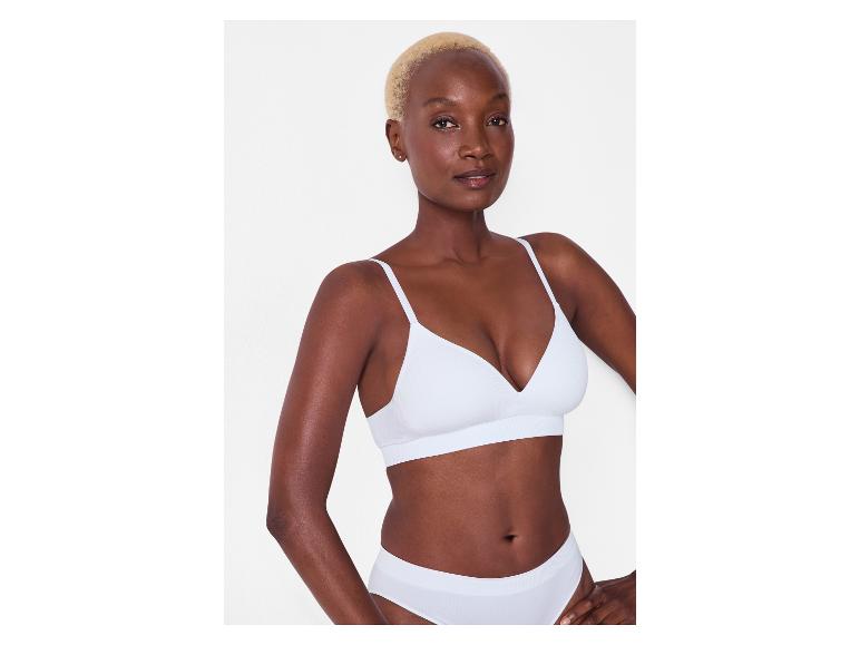 Vrouw draagt een witte geribbelde beha en slip.