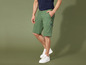 Man draagt groene cargo shorts en witte sneakers.