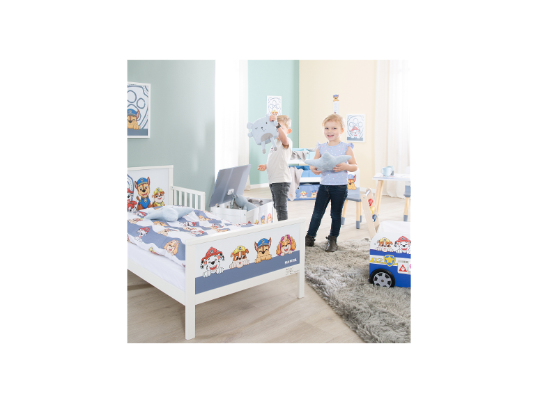 Kinderkamer met bed, speelgoedkist en tafel in puppythema.