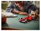Blije jongen speelt met een rode LEGO Ferrari Formule 1-racewagen op een tafel.