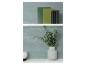Groene en zwarte boeken op de bovenste plank, eucalyptus in een vaas en een witte kaars op de onderste plank.