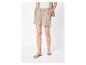 Vrouw in beige short met trekkoord, bijpassend overhemd en platte sandalen.