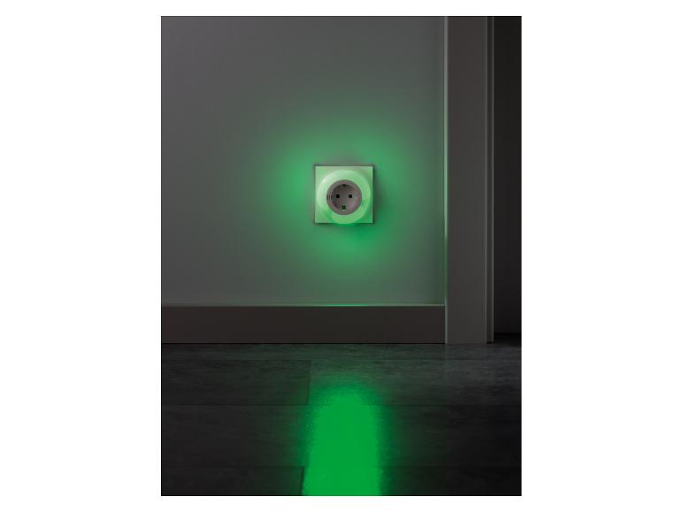 Wandcontactdoos met groen nachtlampje dat de vloer verlicht.
