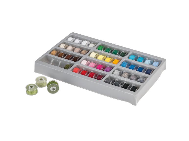 Set naaigarenklosjes in diverse kleuren, georganiseerd in een grijze doos.