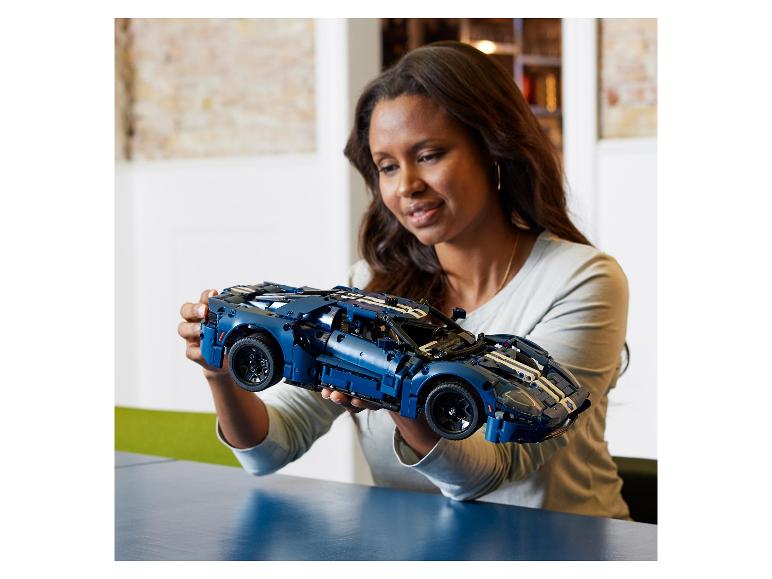 Vrouw houdt een gedetailleerd Ford GT sportwagenmodel vast, gemaakt van bouwstenen.