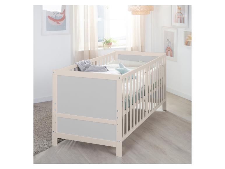 Licht houten babybedje met grijze zijkanten in een lichte kamer met wanddecoraties.