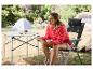 Vrouw zittend op een opvouwbare campingstoel, een kaart lezend aan een campingtafel.