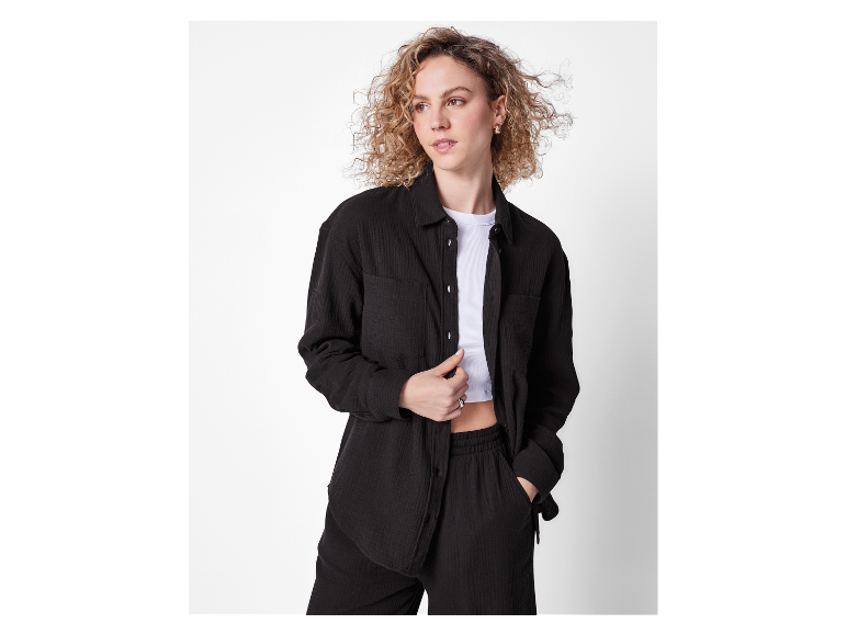 Model in een zwart katoenen pak, broek en overhemd.