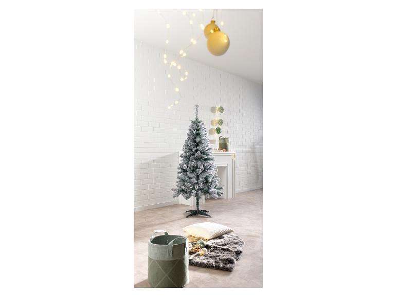 Besneeuwde kerstboom in een feestelijk versierde kamer.