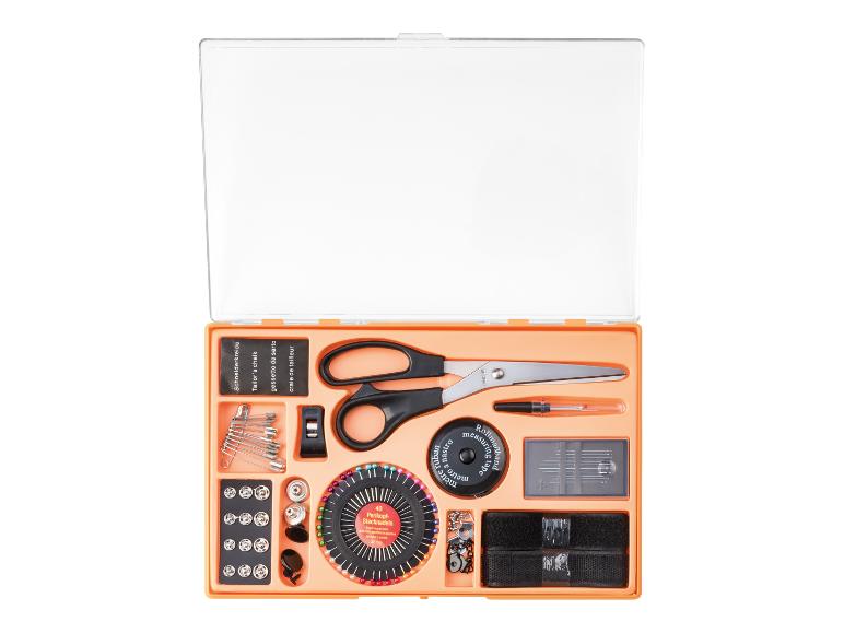 Naaiset met schaar, spelden, meetlint en kleermakerskrijt in een oranje doos.