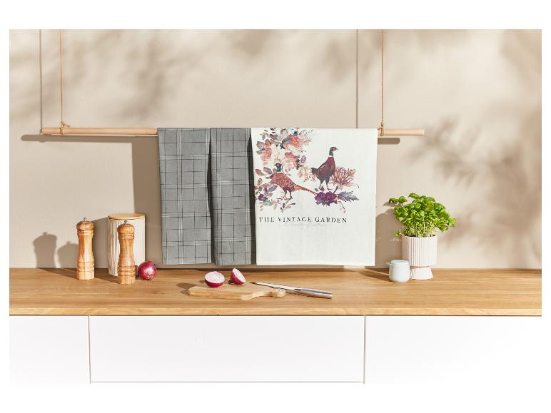 Keukenhanddoeken met bloemen- en fazantenmotieven, hangend aan een houten stok.