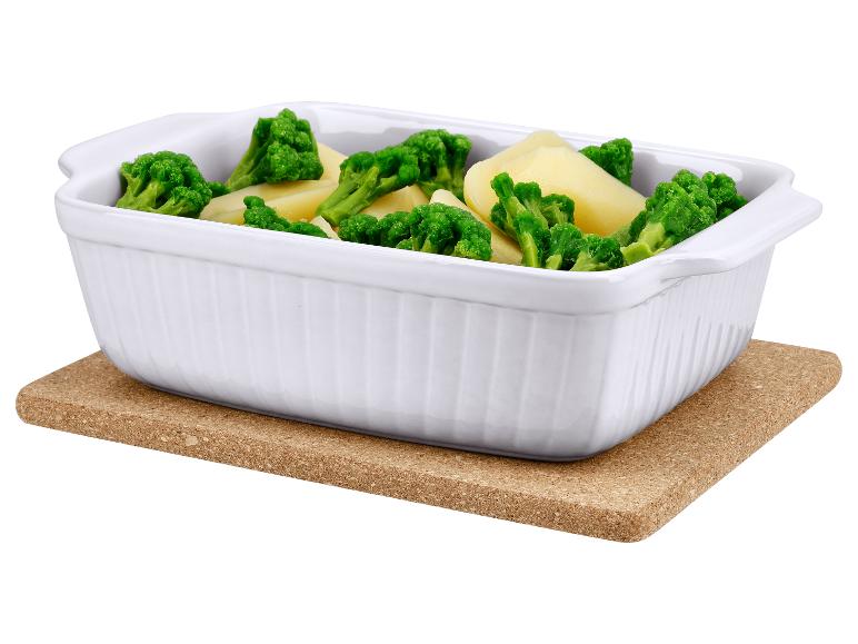 Witte keramische ovenschaal met broccoli en aardappelen op een kurkmat.
