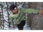 Man met hoofdlamp en groene jas in besneeuwd bos.