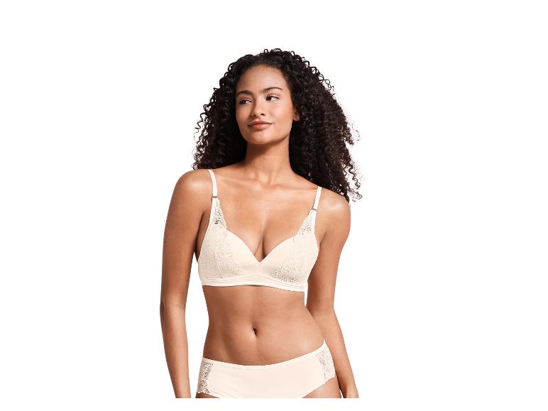 Een vrouw draagt een beige bh met kant en bijpassende slip.