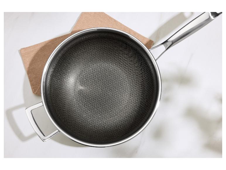 Koekenpan met honingraatbodem en metalen handvat op een bruine doek en wit oppervlak.